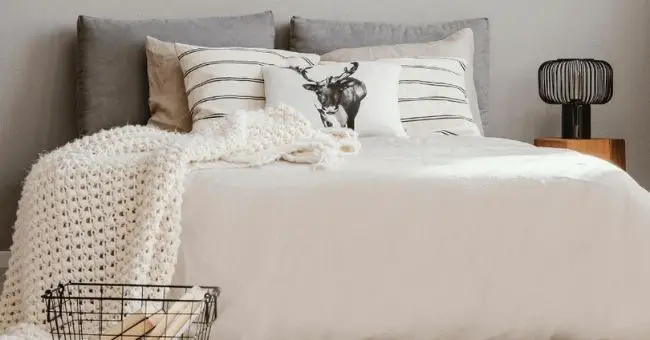 bed with white knitted throw and accent pillows