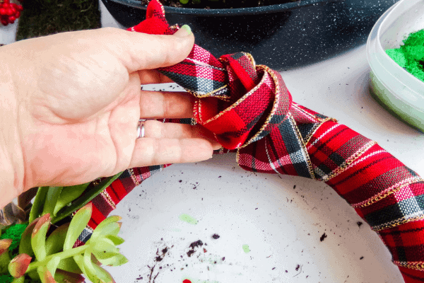 plaid red ribbon in knot tied around wreath as hanger